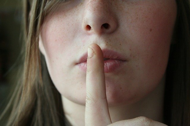 woman with her finger to her lips to indicate that silence is desired